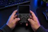 Black console held at a gaming desk